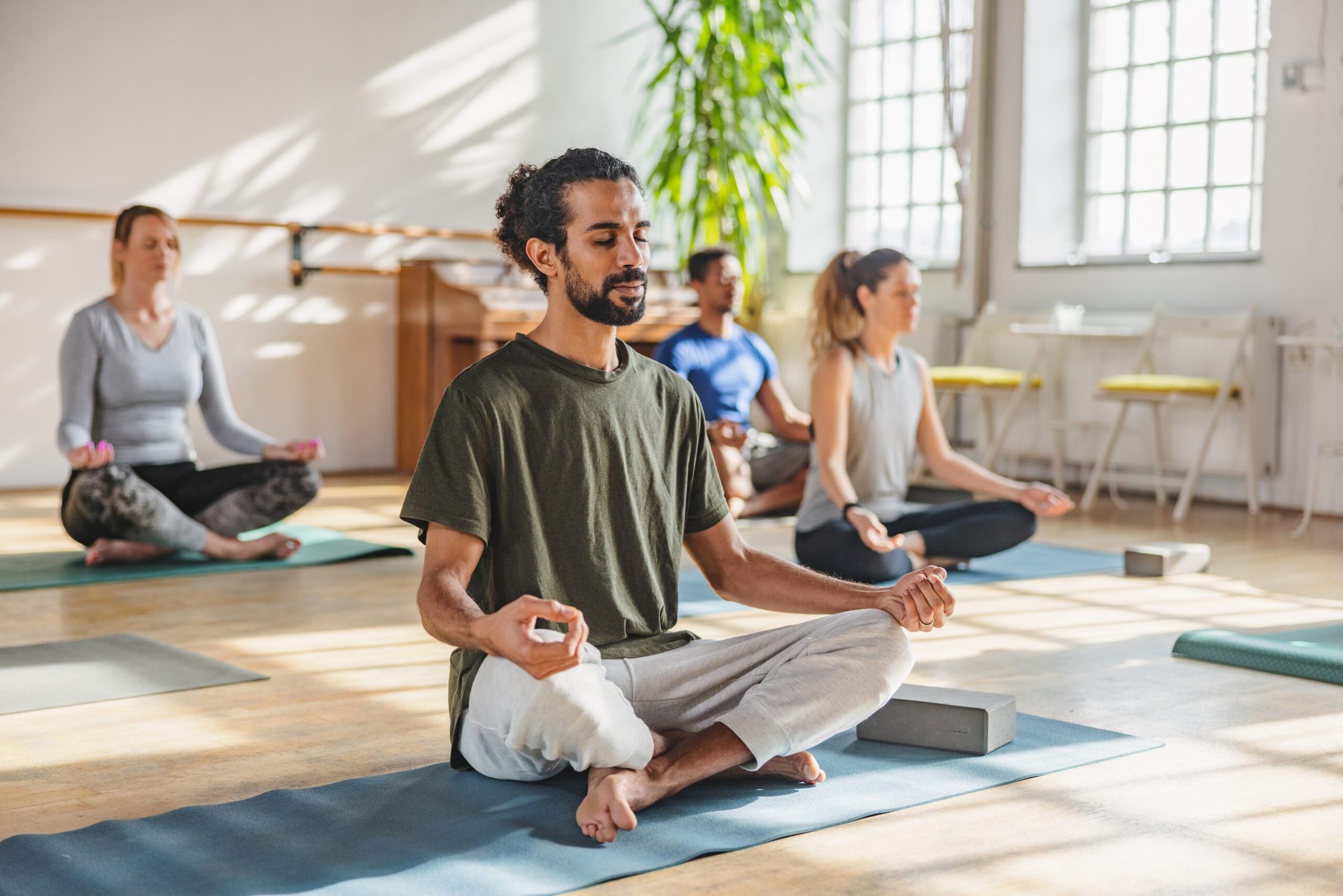 A breathwork class seated cross-legged on mats in a bright room