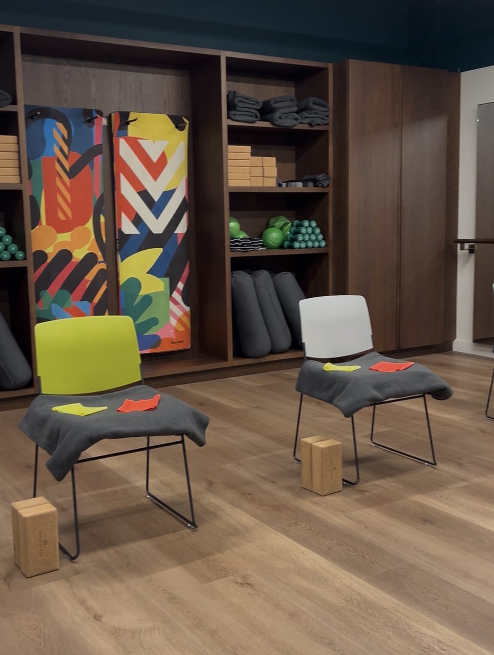A room with coloured chairs, folded mats, blocks and a painted mural