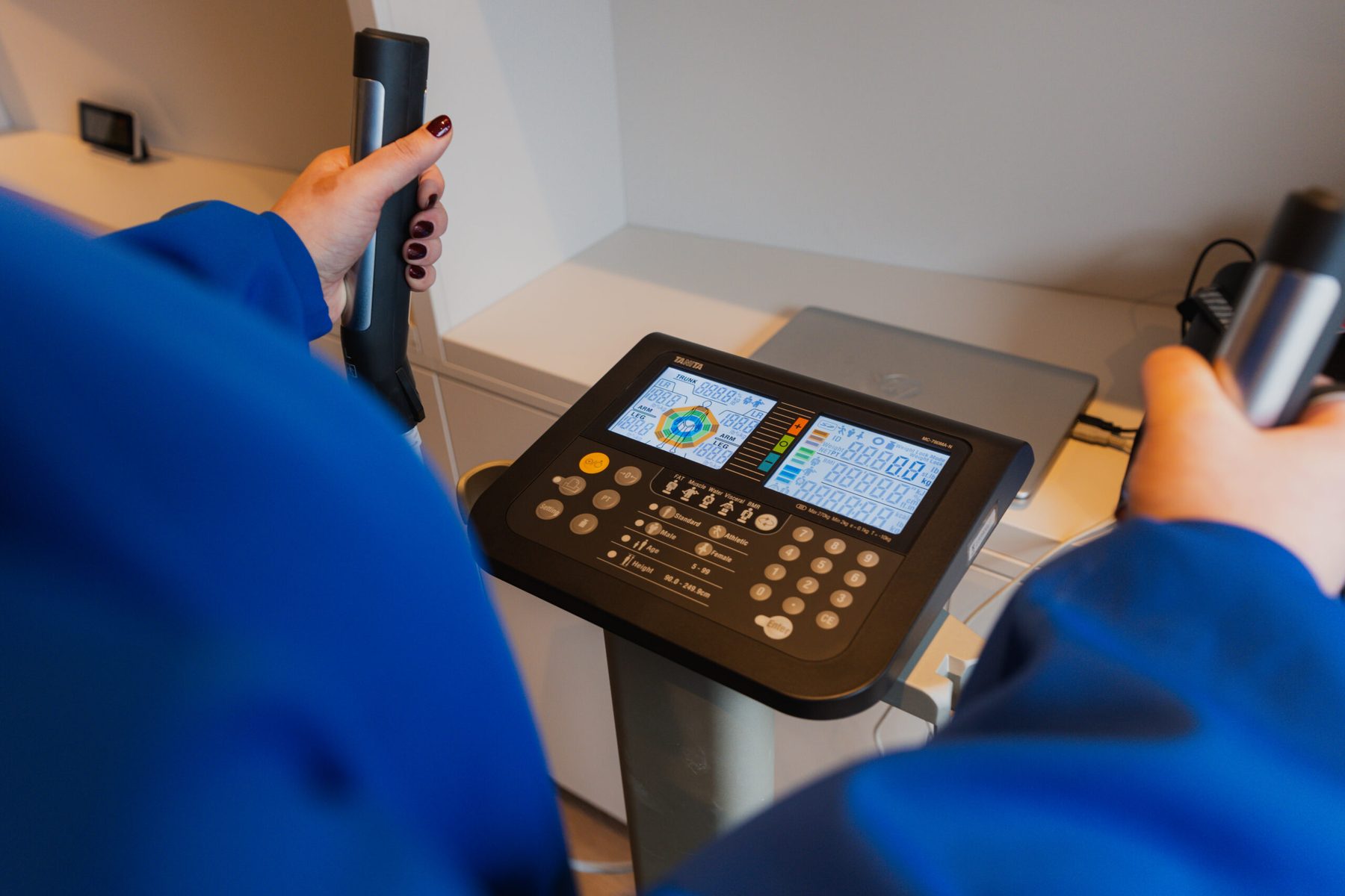 A hand operating the control panel of a clinical measuring device
